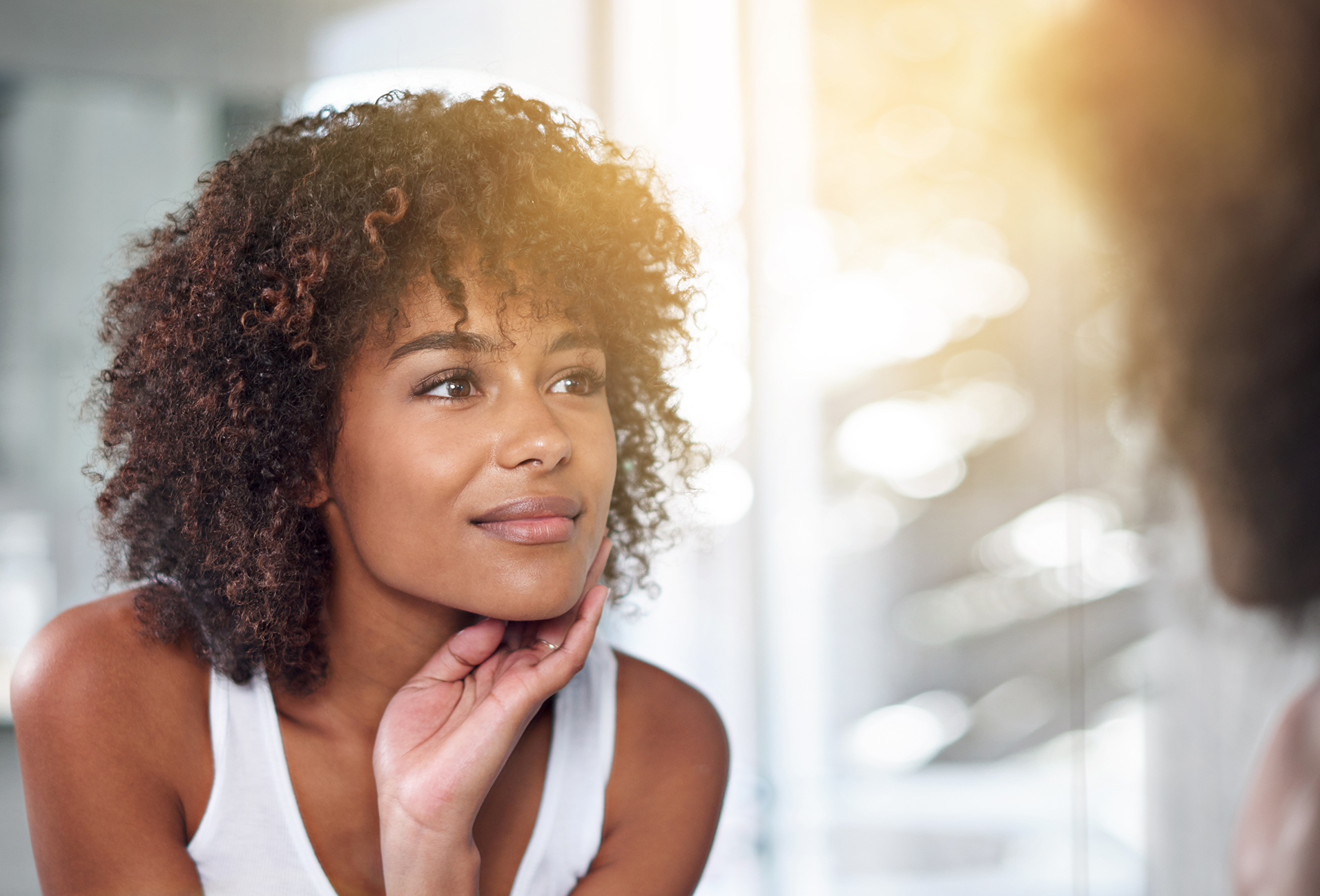 woman with curly hair looking in a mirror