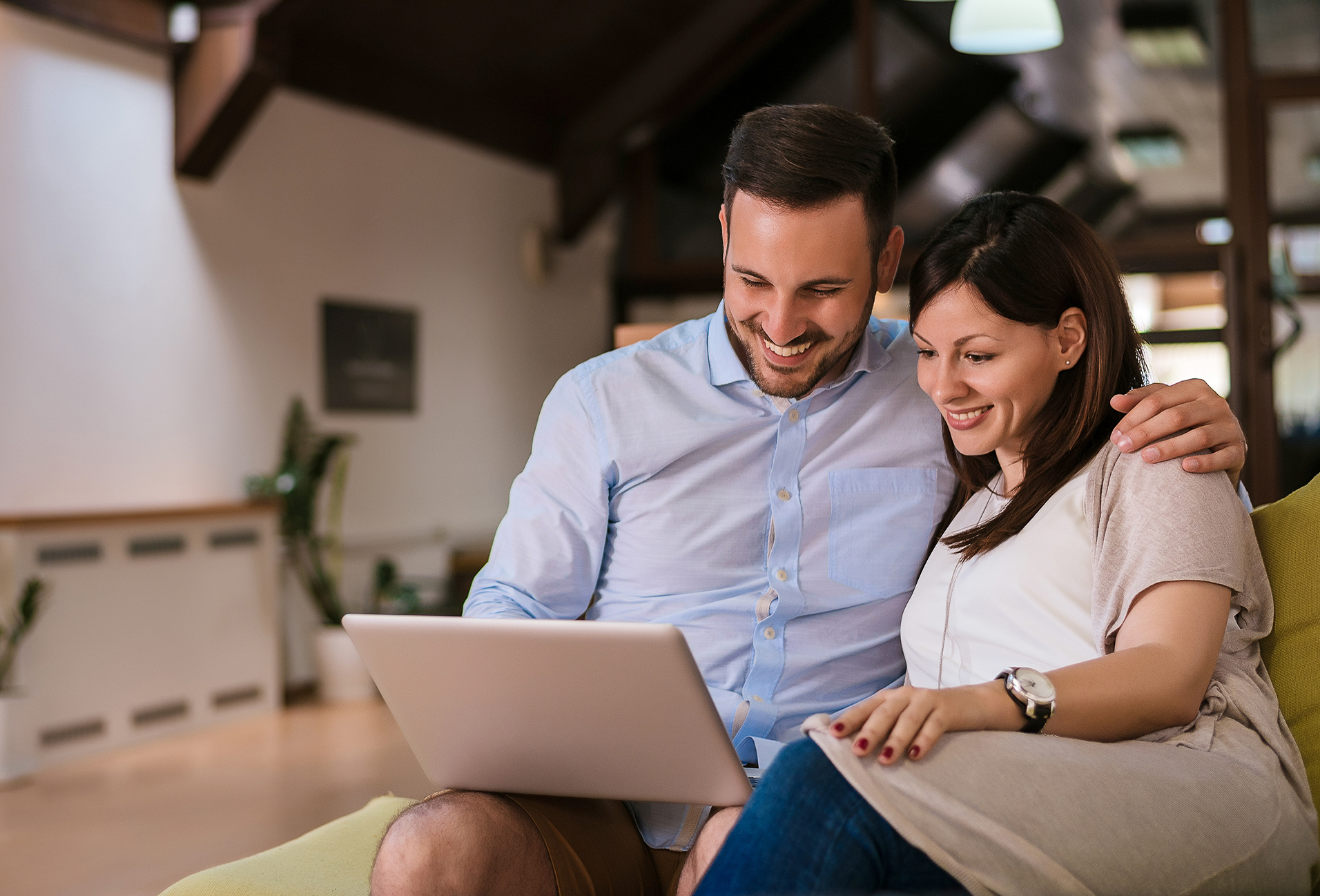 couple embracing while looking at a laptop