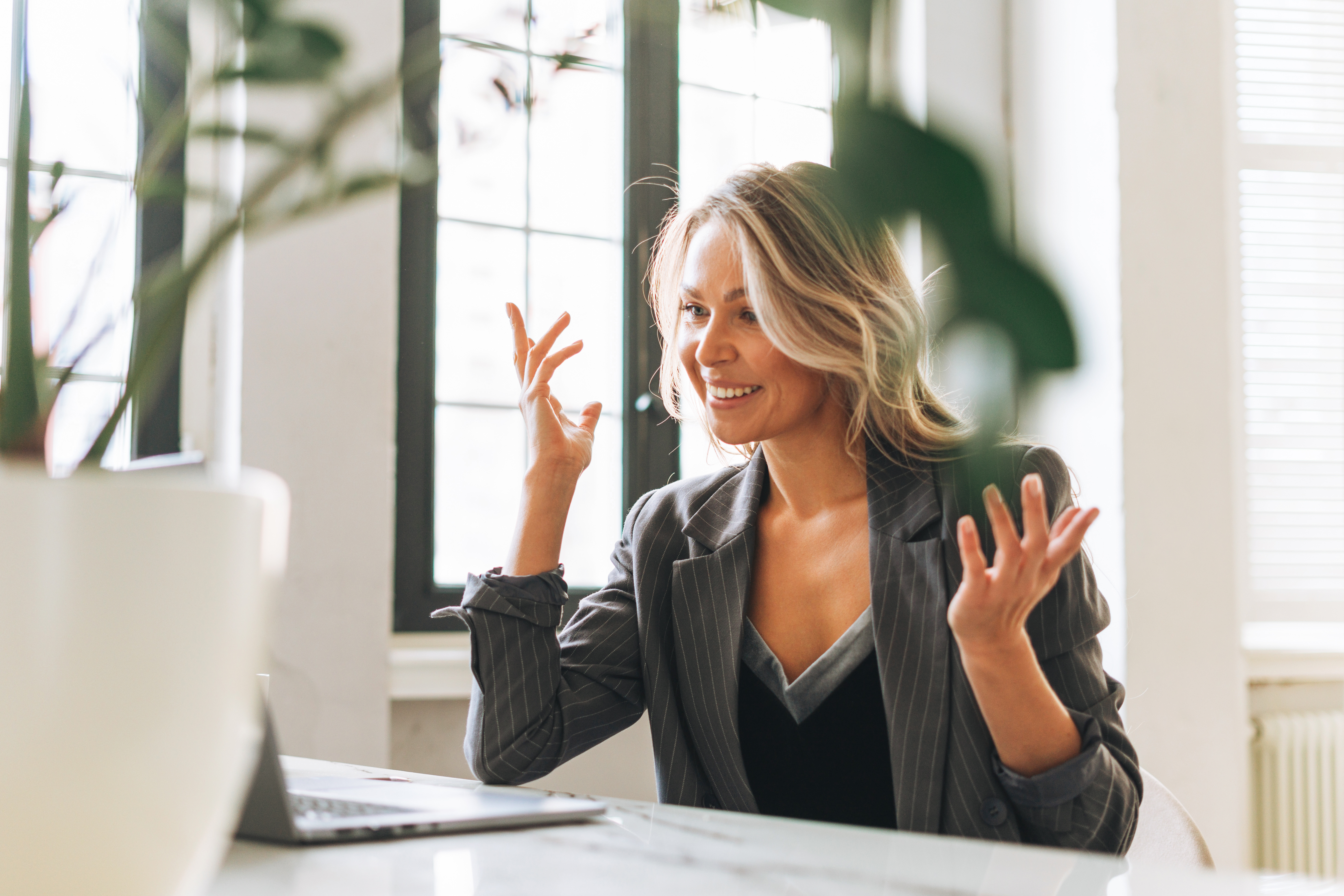 blonde woman sitting at a desk with her hands up in front of her