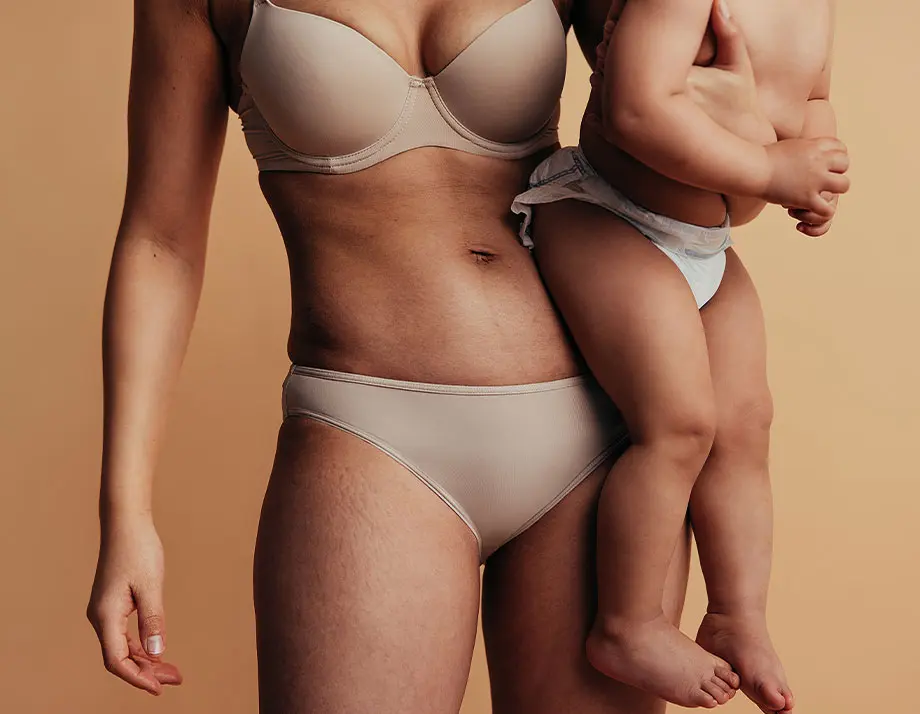 woman in a bikini holding a baby in her arms