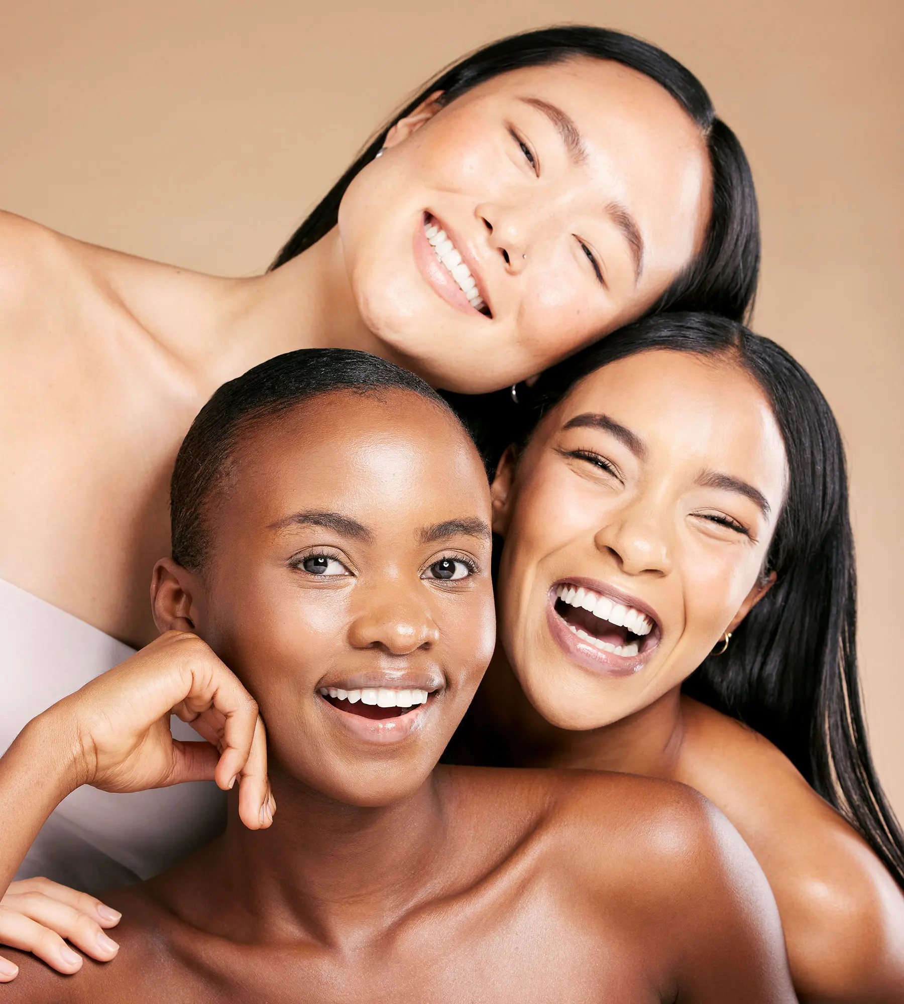 Three women with healthy and diverse skin tones smiling